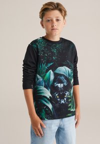 Pitkähiha musta collegepaita, jossa on eläviä viidakon kuvastoja, kuten pantteri ja vihreät lehdet. Suunnittelussa on myös tekstuuripainatus.