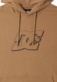 Brun huvtröja med snörning, med en stor svart DC-logotyp och stjärndesign på framsidan. Texturen verkar mjuk och slät.