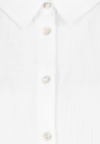 White collared shirt with a textured fabric, featuring five light-colored buttons along the front placket.