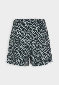 Pantalones cortos negros con un estampado floral que presenta pequeñas flores blancas y verdes, cintura elástica, corte holgado y textura de tela suave.