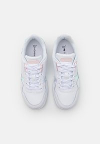 Białe sneakersy z pastelowymi akcentami, o gładkiej powierzchni, z zapięciem na sznurówki i teksturowaną podeszwą, oznaczone napisem "Lacoste".