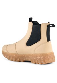 Beige ankelstövlar med svarta elastiska sidopaneler, dragflikar fram och bak samt en texturerad genomskinlig gummisula.
