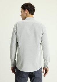 Camicia a maniche lunghe grigia chiaro con un motivo testurizzato, colletto a punta e polsini con bottoni. Vestibilità sartoriale con orlo curvo.