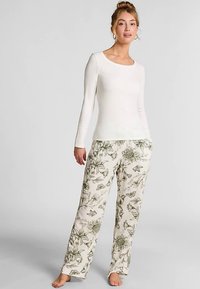 Wit shirt met lange mouwen, gecombineerd met crèmekleurige broek met een bloem- en vlinderpatroon in groene tinten. Zachte stof, losse pasvorm, casual stijl.