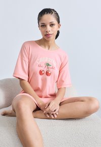 Απαλό ροζ υπερμεγέθες T-shirt με κοντά μανίκια, με κείμενο "CHERRISH the Night" και γραφικό κεράσι. Μαλακό βαμβακερό ύφασμα.