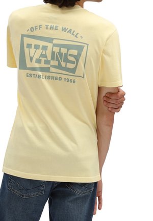 Geel katoenen t-shirt met een grote blauwe afbeelding met "VANS" en "ESTABLISHED 1966" op de achterkant. Korte mouwen en een ontspannen pasvorm.
