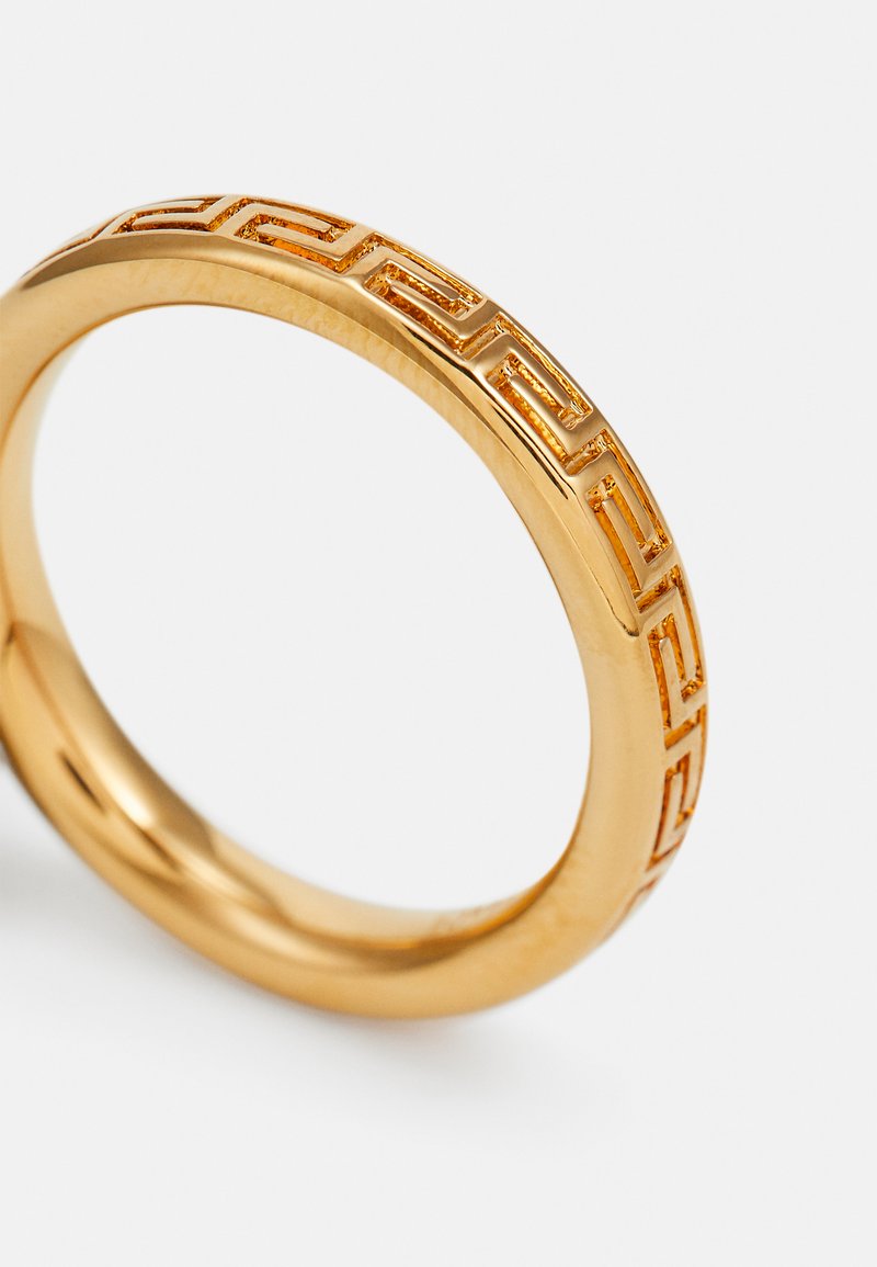 Anello d'oro con una finitura liscia e un motivo geometrico lungo la fascia. Forma circolare, con una texture lucida e una brillantezza metallica.