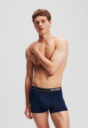 Tengerészkék boxeralsó fekete derékpánttal, amelyen fehér logó található. Sima textúra és karcsúsított kialakítás, mindennapi viseletre alkalmas.