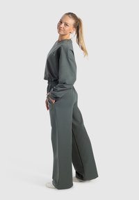 Grå athleisure sæt bestående af en løstsiddende, cropped sweatshirt og brede bukser med elastisk talje. Blødt stof, minimalistisk design.