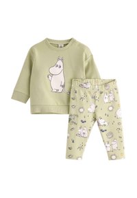 Vihreä kaksiosainen asu, joka sisältää hupparin, jossa on Moomin-hahmon graafinen kuvasto, ja siihen sopivat leggingsit, joissa on eri Moomin-sceneja.