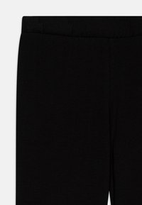 Zwarte broek met een gladde textuur, voorzien van een elastische tailleband. De stof lijkt lichtgewicht en flexibel, geschikt voor casual gebruik.
