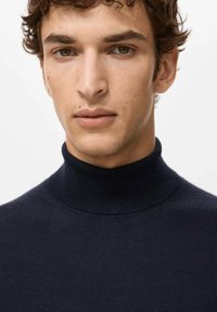 Marineblauwe coltrui gemaakt van zachte stof, met een aansluitend ontwerp en geribbelde hals. Gladde textuur met minimale details.