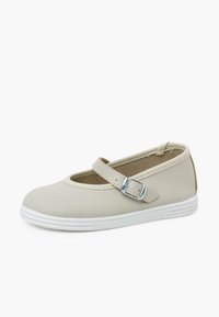 Zapato Mary Jane beige con puntera redondeada, suela blanca plana y una correa con un hebilla plateada. Material sintético suave y diseño minimalista.