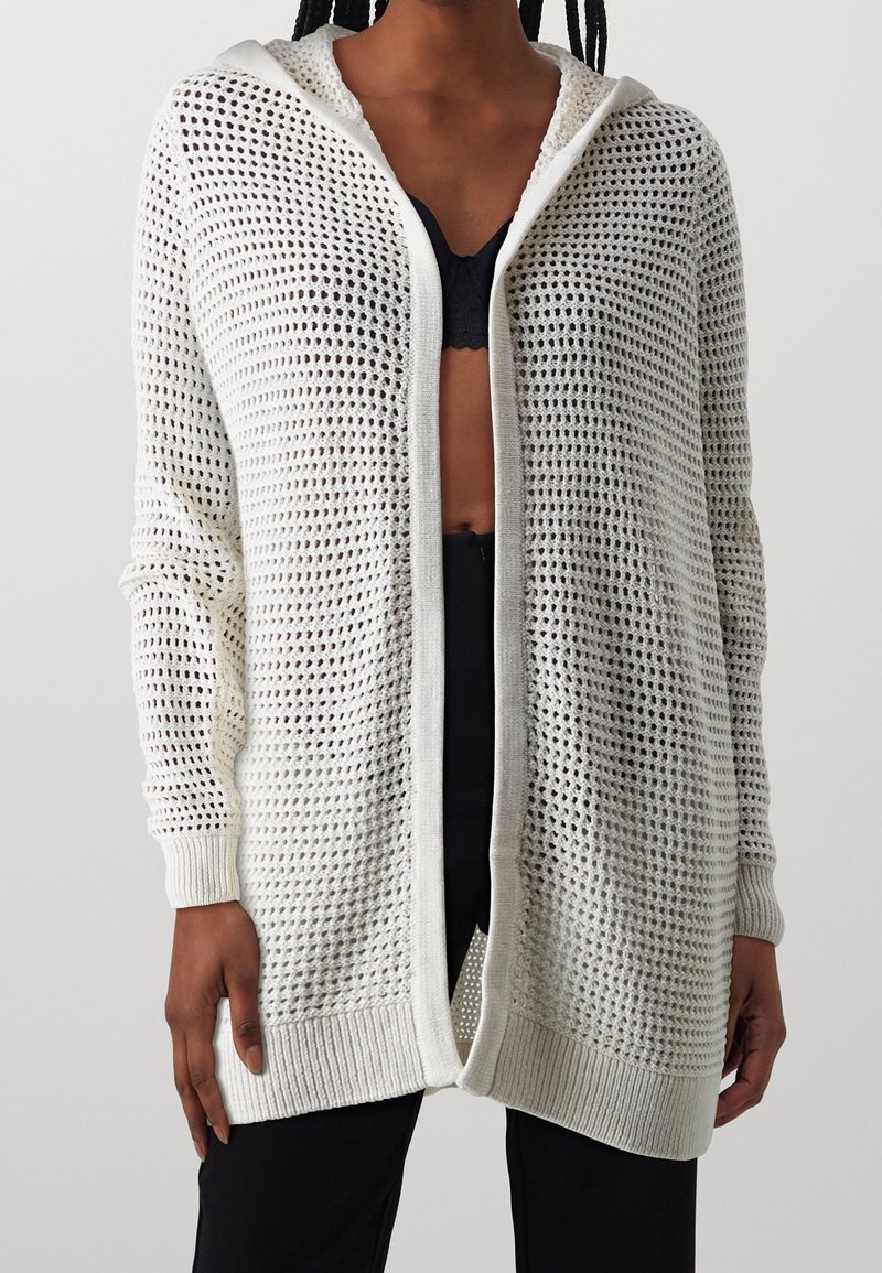 Bílý pletený cardigan s volným, otevřeným designem, který má kapuci, žebrované manžety a texturovaný vzor po celé ploše.
