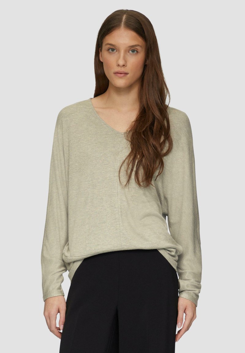Helles graues langärmliges Pullover mit V-Ausschnitt, lässiger Passform, weichem Material und seitlichen Schlitzen, kombiniert mit schwarzen Hosen.