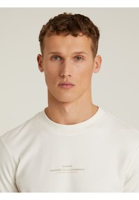 Weißes Sweatshirt mit Rundhalsausschnitt und geripptem Design, das dezente Markenlogo in hellem Beige aufweist. Entworfen mit einem entspannten Schnitt und klassischem Ausschnitt.