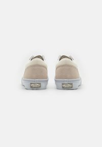 Zapatillas Vans con un upper de cuero y ante en color beige y blanco roto, con un logo distintivo en el talón y una suela de goma blanca.