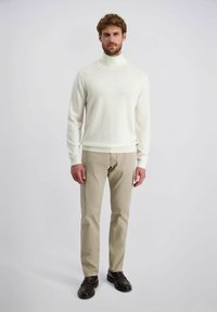 Cremfarbener Rollkragenpullover kombiniert mit beigen Hosen im geraden Schnitt und braunen Lederschuhen, mit glatter Textur und schlichter Gestaltung.