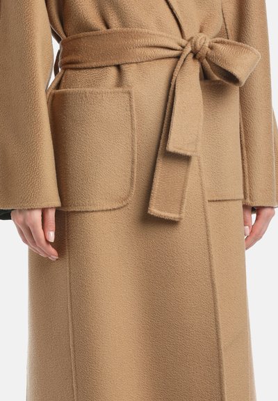 Beige gyapjúszövet köntös, textúrált felülettel, túlméretezett zsebekkel és derékon megkötött övvel.