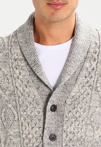 Cardigan grigio lavorato a maglia con colletto a scialle, caratterizzato da motivi a treccia e due bottoni scuri. Tessitura calda con un design aperto e rilassato.
