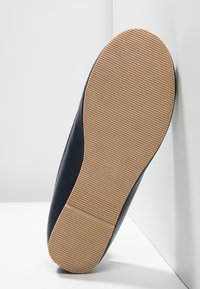 Scarpa in pelle nera con finitura liscia, forma arrotondata e suola in gomma rigata color marrone chiaro. Taglia contrassegnata come 32 sulla suola.