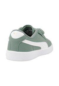 Sneaker en suede vert avec des accents blancs, dotée d'un col rembourré, d'une languette texturée et d'un logo doré sur le talon. Semelle en caoutchouc avec un motif de traction.