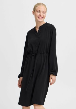 Schwarzes Hemdkleid mit langen Ärmeln, elastischem Bund und lockerer Passform. Hergestellt aus glattem Stoff mit einem minimalistischen Design.