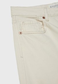 Beiga jeans med en klassisk design, som har bakfickor, kopparnitar och synlig sömnad. Mjuk textur och hållbart material.