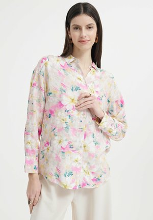 Langarm-Hemd mit Knöpfen aus leichtem Stoff, mit einem floralen Muster in Rosa-, Weiß- und Grüntönen auf einem hellen Hintergrund.