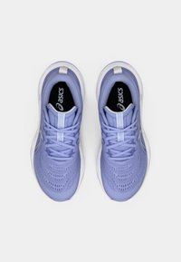 Fioletowe buty sportowe z oddychającą siateczką, białymi akcentami i wyściółką przy kostce. Posiadają teksturowaną powierzchnię i sznurowane zapięcie.