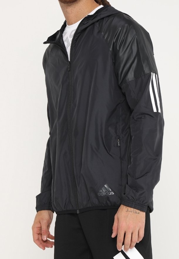 Czarna, lekka kurtka z kapturem, z błyszczącymi czarnymi panelami na ramionach i trzema białymi paskami na rękawach. Kieszenie zapinane na zamek.