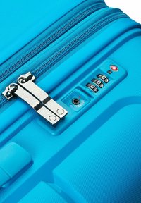 La maleta rígida azul presenta una superficie texturizada, dos cremalleras y una cerradura de combinación integrada con el logo de la TSA.