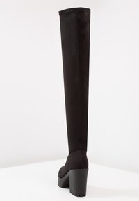 Stivali neri in suede alti fino al ginocchio con tacco spesso, caratterizzati da un design elegante e una texture liscia, mostrano la vista posteriore senza motivi distintivi.