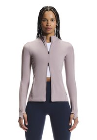 Long-sleeve, light pink zip-up jacket with a high collar, fitted design, thumb holes, and flat seams for comfort. Fabric appears smooth and stretchy.