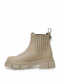Botas de tobillo de cuero beige con paneles laterales elásticos acanalados, suela gruesa y una tirador en la parte posterior para ponérselas fácilmente.