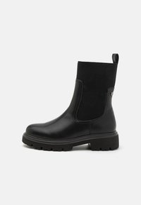 Botas de tobillo negras con un acabado de cuero suave, paneles laterales elásticos acanalados, tirador y suela de goma gruesa para una mejor tracción.