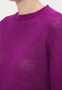 Lila stickad tröja med rund hals. Lättvikts, texturerat tyg; har en lös passform med synligt stickat mönster.