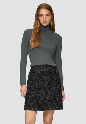 Grijze turtleneck top gecombineerd met een zwarte rok met een textuur en glinsterende afwerking. De outfit heeft lange mouwen en een aansluitende pasvorm.