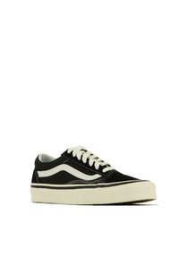Scarpe da ginnastica nere in tela con accenti e lacci bianchi. Presentano un design a profilo basso e una suola in gomma bianca spessa. Dettaglio iconico della striscia laterale.
