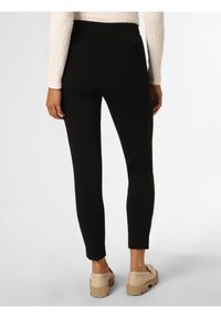 Mustat slim-fit housut, joissa on sileä pinta, takataskut ja korkea vyötärö. Yhdistetty beigeihin, paksupohjaisiin kenkiin.