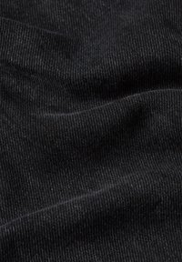 Black denim fabric with a smooth texture and diagonal weave pattern, showing subtle variations in color and depth.