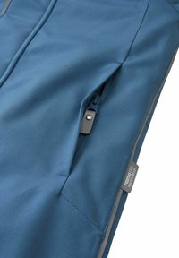 Niebieska wodoodporna tkanina o gładkiej fakturze; posiada boczną kieszeń na zamek błyskawiczny oraz metkę marki "rematec waterproof."