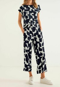 Marinblå och vit mönstrad klädsel bestående av en kortärmad topp och vida byxor, tillverkad av mjukt tyg med en avslappnad passform.