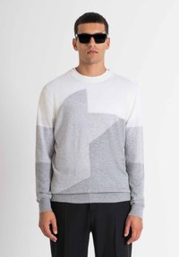 Maglione leggero bianco e grigio con un motivo geometrico a stelle. Presenta un collo a giro e polsini e orlo a coste.