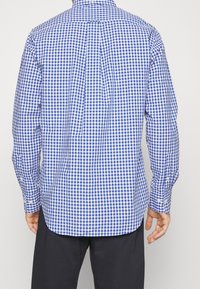 Sininen ja valkoinen ruudullinen pitkähihainen paita klassisella kauluksella ja napillisilla hihansuilla, valmistettu kevyestä kankaasta, jossa on kaareva helma.