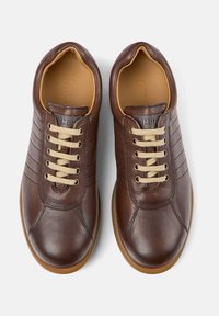 Pair of brown leather casual shoes with beige laces and gum rubber soles, viewed from above on a white background.
