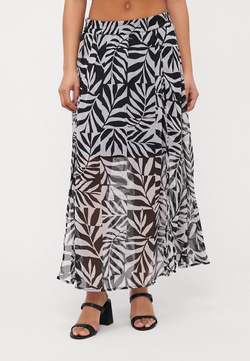 Maxi skirt in sheer fabric featuring a black and white leaf pattern. Elastic waistband, flowy design, and side slit for movement.
