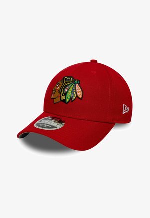 Roter Baseball-Cap mit einem gestickten Logo eines amerikanischen Ureinwohnerkopfes und einem New Era Flaggenlogo an der Seite.