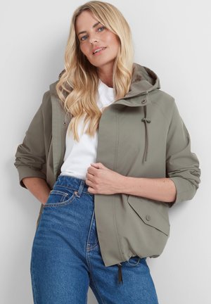 Olive green lightweight jacket with a drawstring hood, snap buttons, and front pockets; worn over a white shirt and blue jeans.