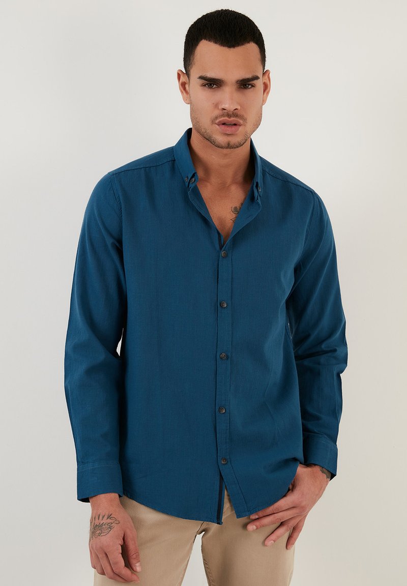 Knoopshirt in diep teal stof, lange mouwen, met een klassieke kraag, een voorpand met knopen en een ontspannen pasvorm.